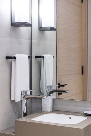 A modern bathroom with a rectangular sink, two towel racks, a mirror, and a door. - Modern Coastal Luxe  JBR Apartment (Dubai)