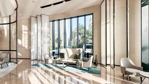 Un vestíbulo espacioso con diseño moderno, que incluye una zona de estar con sofás y sillones, ventanas amplias con vistas a la ciudad y un piso de mármol pulido.