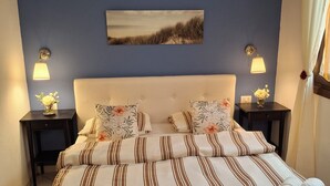 Una cama bien hecha con ropa de cama a rayas, dos mesitas de noche con lámparas y un cuadro colgado en la pared.