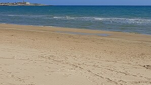 Una playa con cielo despejado y mar tranquilo.