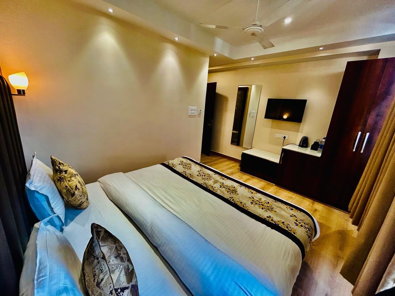 A hotel room with a large bed, a desk, a flat-screen TV, and a wardrobe.