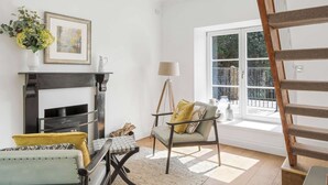 Un salon avec une cheminée, un fauteuil, une table et une fenêtre donnant sur un beau paysage.