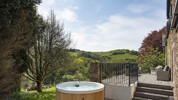 Un bain à remous sur une terrasse en bois, avec vue sur un paysage verdoyant.