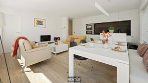 A modern living room with a sofa, a dining table, and a kitchen area with appliances. - James Ensor Zon - beach fun in Oostduinkerke (Oostduinkerke)
