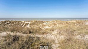 Un paysage côtier avec des dunes et un ciel dégagé.