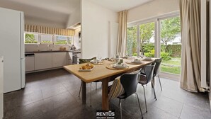 Une cuisine moderne avec un coin repas, de grandes fenêtres et une vue sur le jardin.