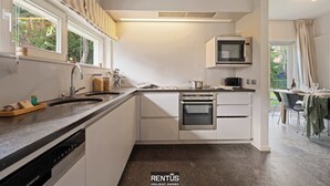 Une cuisine moderne avec des meubles blancs, un four encastré, un four à micro-ondes et un lave-vaisselle.