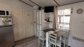 A compact kitchen with a microwave, refrigerator, and a small dining table with chairs. - Mh 229 - La Tremblade: Comfortable Mobile Home for Families, Near Beach & City Center (La Tremblade)