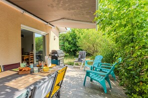Eine Terrassengaststätte mit Esstisch, Grill und Gartenmöbeln.