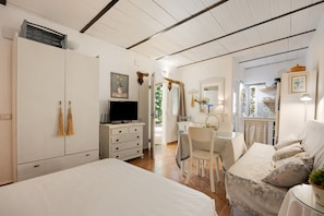 A bedroom with a bed, a TV, a desk, and a chair.