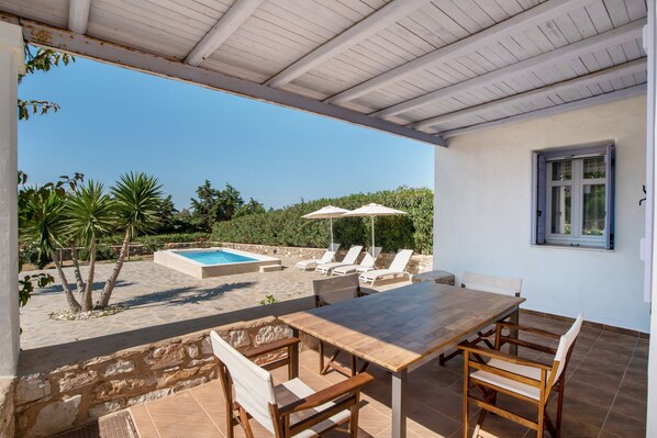 Un'area esterna riparata con piscina, poltrone da relax e tavolo da pranzo.