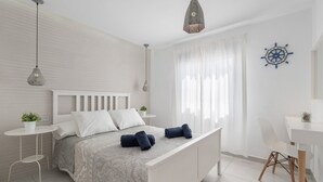 A modern bedroom with a bed, bedside tables, a desk, and a decorative wall piece. - Vacation 'Princesa Teguise' with Shared Pool, Shared Terrace and Wi-Fi (Tías)