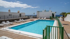 A rooftop swimming pool with lounge chairs, a clear sky, and a view of the sea. - Vacation 'Princesa Teguise' with Shared Pool, Shared Terrace and Wi-Fi (Tías)