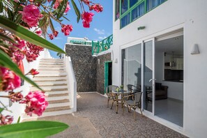 Ein Gebäude mit einer Treppe, die zu einem Balkon führt, einem Essbereich mit Stühlen und einem Tisch sowie einer grünen Tür.