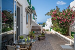 Ein Balkon mit Glastisch, Stühlen und Topfpflanzen.