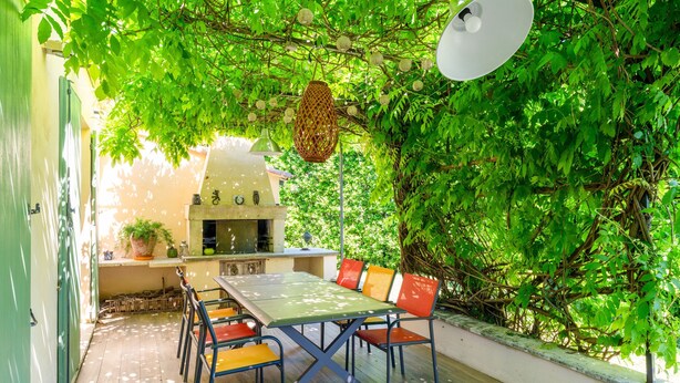 An outdoor dining area with a table and chairs, surrounded by greenery and a pergola. - Villa 'Charming with Pool' with Private Pool, Wi-Fi and Air Conditioning (Fontvieille)
