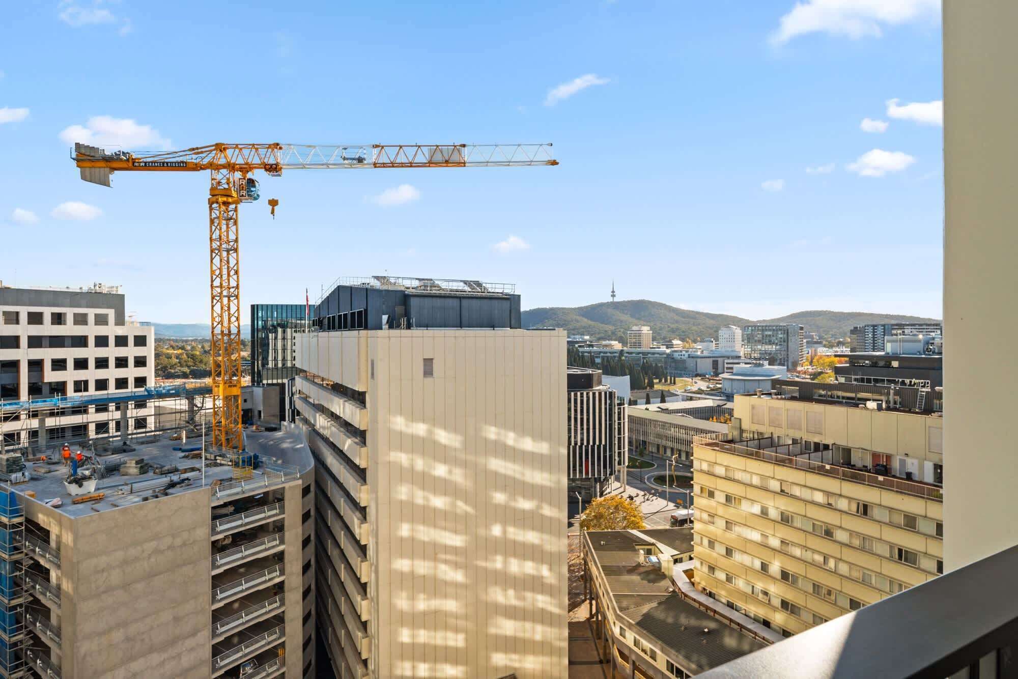 A construction site with a crane, modern buildings, and a view of the cityscape.