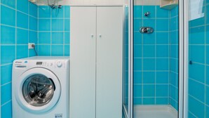 A bathroom with blue tiles, a washing machine, and a shower. - Apartment 'Piazzetta Garden' with Sea View, Private Terrace and Air Conditioning (san teodoro)