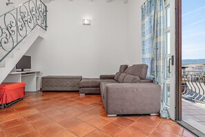 Una sala de estar con un sofá seccional, un televisor y una escalera.