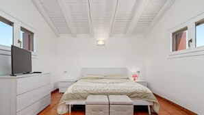 A bedroom with a bed, a TV on a dresser, a nightstand, and a window. - Apartment 'Piazzetta Garden' with Sea View, Private Terrace and Air Conditioning (san teodoro)