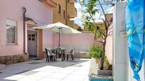 Un patio con mesa y sillas, una piscina y un edificio de fachada rosa.