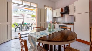 Una cocina con armarios blancos, una mesa de comedor de madera y vistas al exterior.