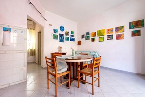 Uma sala de jantar com uma mesa redonda, quatro cadeiras e uma parede decorada com diversas obras de arte.
