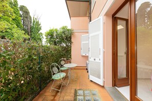Un patio exterior con mesa y sillas, una puerta corredera y una pared con ventanal.