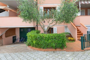 A building with a staircase, a tree, and a bicycle.