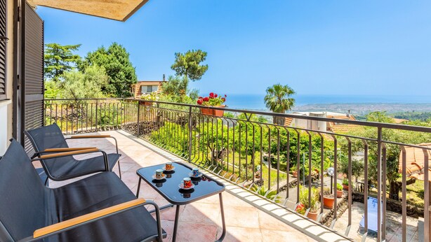 Een balkon met zitplaatsen buiten, een tafel en potplanten.