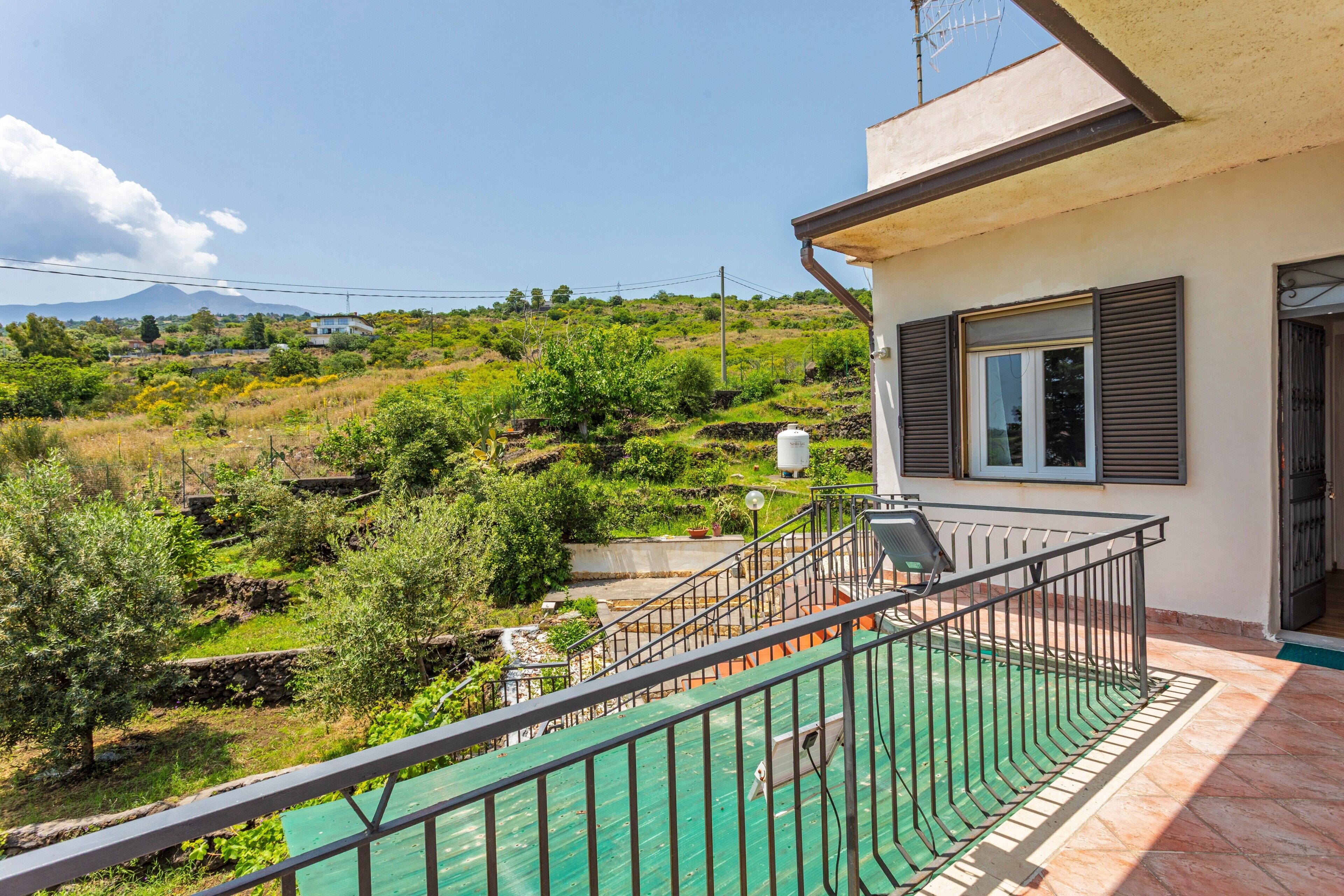 A balcony with a view of a green landscape and a mountain in the distance.