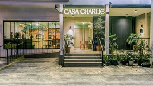 The entrance to a hotel named "Casa Charlie" with a staircase leading up to the entrance, surrounded by potted plants.