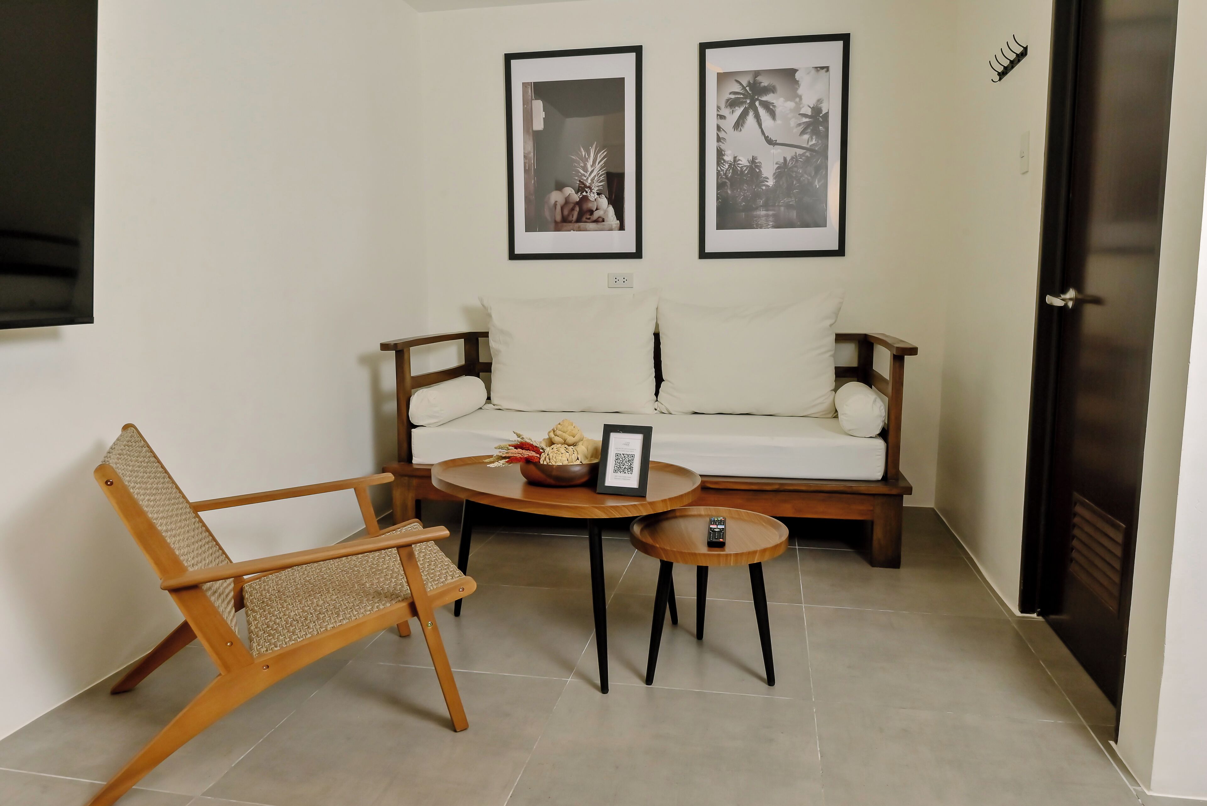 A living room with a sofa, two chairs, a small table, and two framed pictures on the wall.