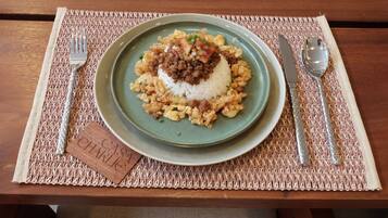 Prato de comida sobre um descanso de mesa, com garfo e colher à esquerda e à direita.