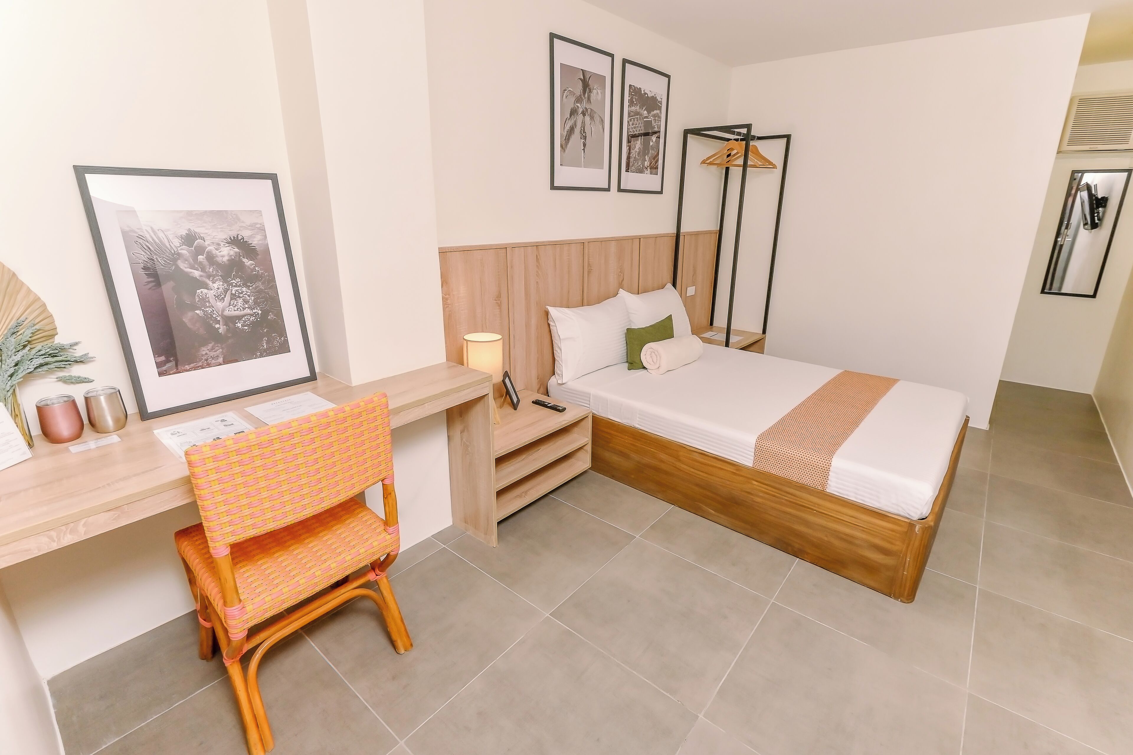 Een hotelkamer met een bed, bureau, stoel, nachtkastje en spiegel.
