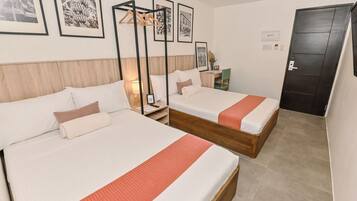 A hotel room with two beds, a wooden headboard, a nightstand, a desk, and framed pictures on the wall.