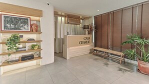 A reception area with a wooden reception desk labeled "CASA CHARLIE," a bench, and potted plants.