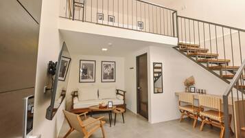 A spacious living area with a sofa, two chairs, a coffee table, and a staircase.