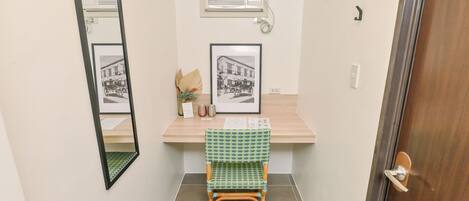A small bathroom with a mirror, an air conditioning unit, a framed picture on the wall, and a chair.