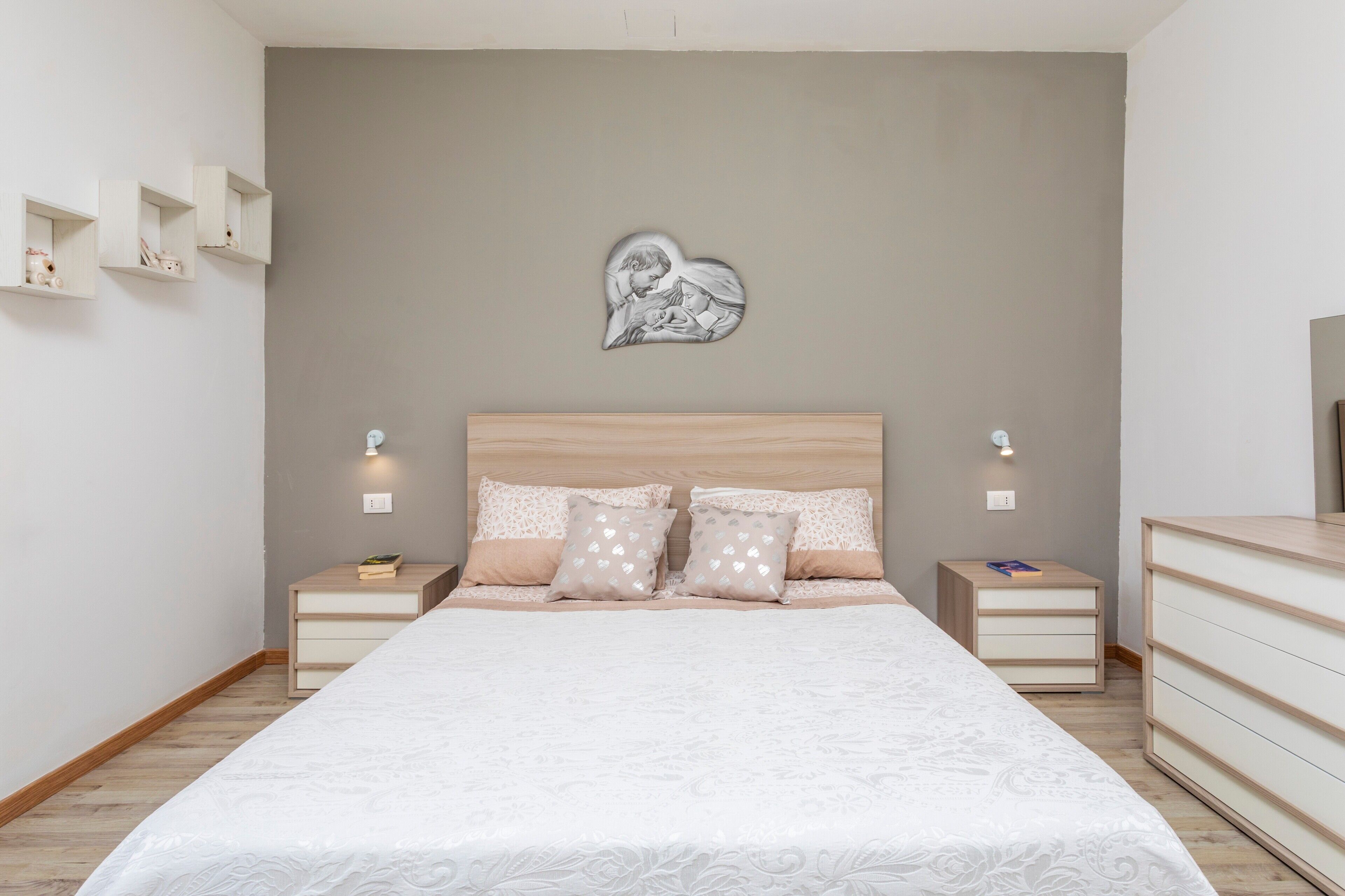 Une chambre à coucher comprenant un lit, des tables de chevet, une commode et un décor mural en forme de cœur.