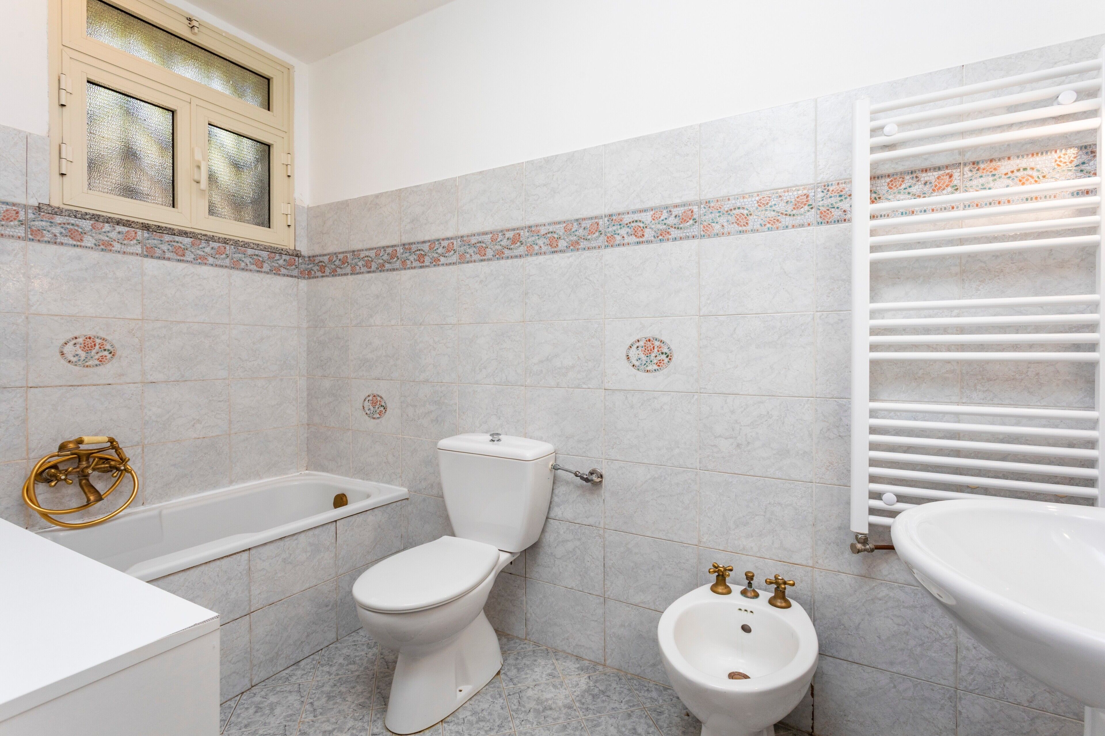 Une salle de bain avec une baignoire, des toilettes, un bidet et un lavabo blanc.