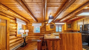 Ein Holzblockhaus-Interieur mit einer Küche, einem Essbereich und einem großen Fenster.