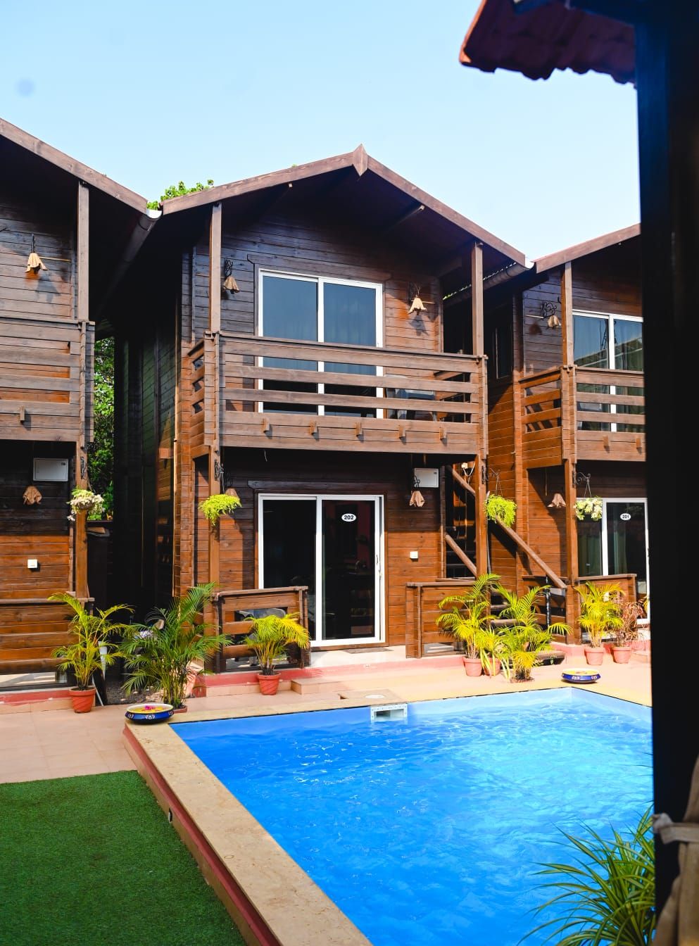 A wooden cabin with a pool, featuring a balcony and a staircase.