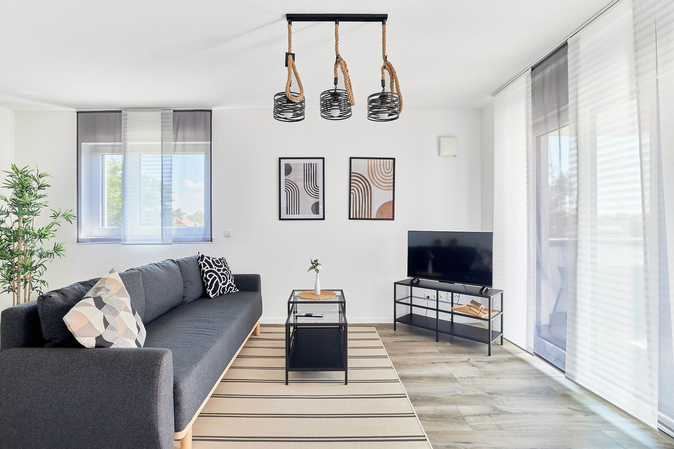 Un salon moderne avec un canapé, une table basse, un téléviseur et des œuvres d’art accrochées au mur.