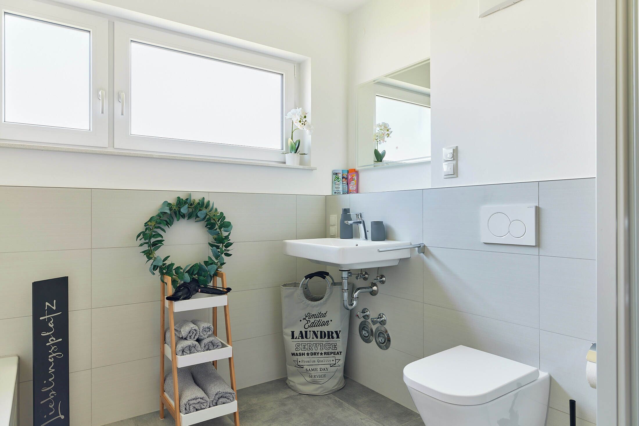 Een badkamer met een wit wastafel, toilet en een plank met handdoeken.