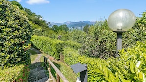 A pathway through a lush garden with a metal lamp post and a stone bench. - Mon Reve Lake View Pool, Stresa (Stresa)