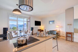 A modern kitchen with a central island, dining area, and a view of the mountains. - Mon Reve Lake View Pool, Stresa (Stresa)
