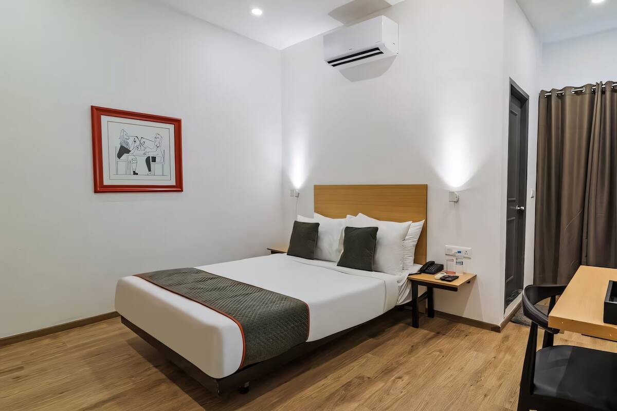 Ein Hotelzimmer mit Bett, Nachttisch und Schreibtisch mit Stuhl.