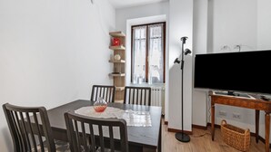 Ein Essbereich mit Tisch, Stühlen, einer Vase und einem Fernseher.