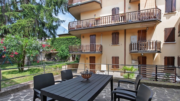 Eine Außenpatio mit Tisch und Stühlen, einem Steinboden und einem Gebäude mit Balkonen.
